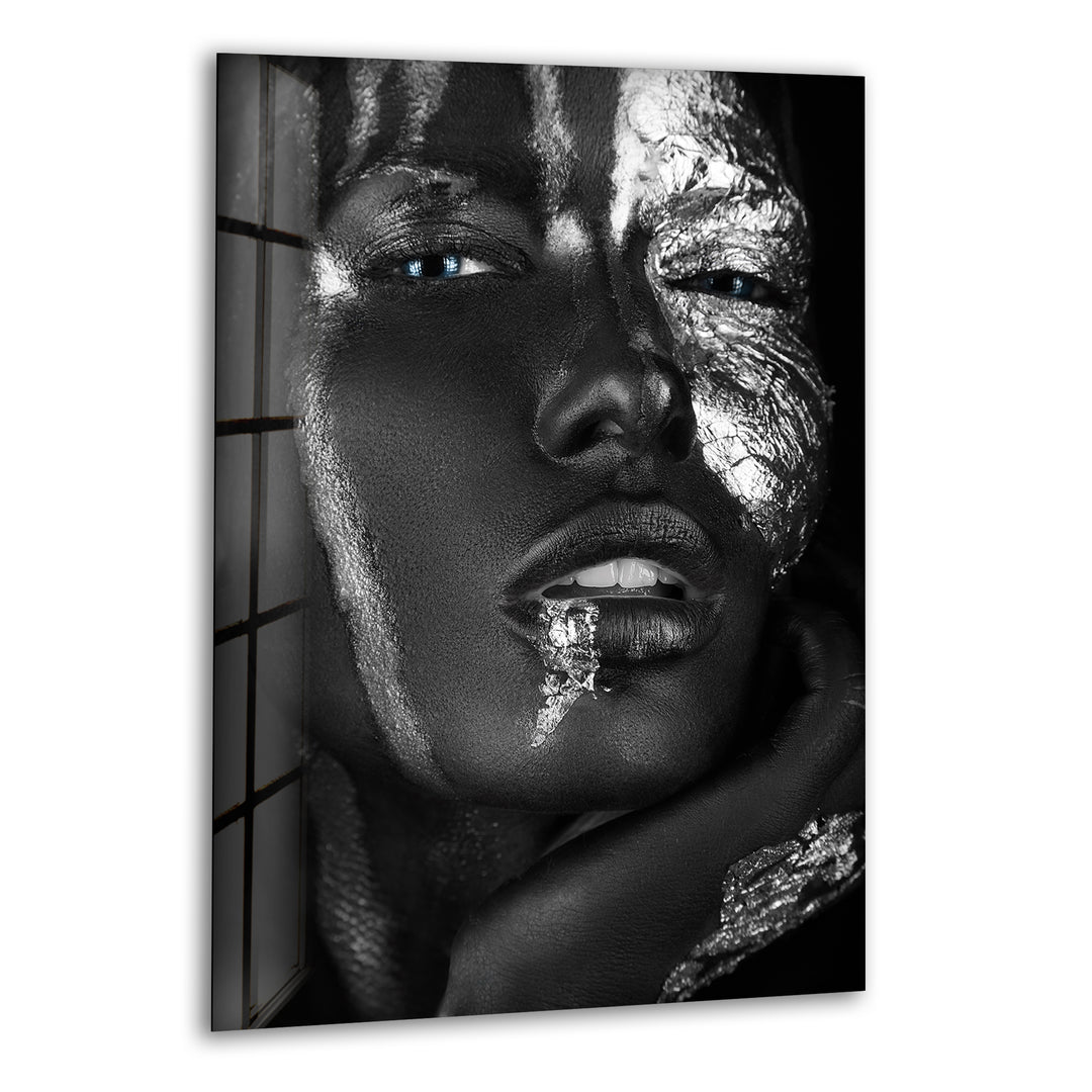 Black and white glass wall art featuring a close-up face with metallic silver textures and vivid blue eyes.