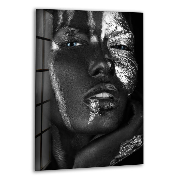 Black and white glass wall art featuring a close-up face with metallic silver textures and vivid blue eyes.