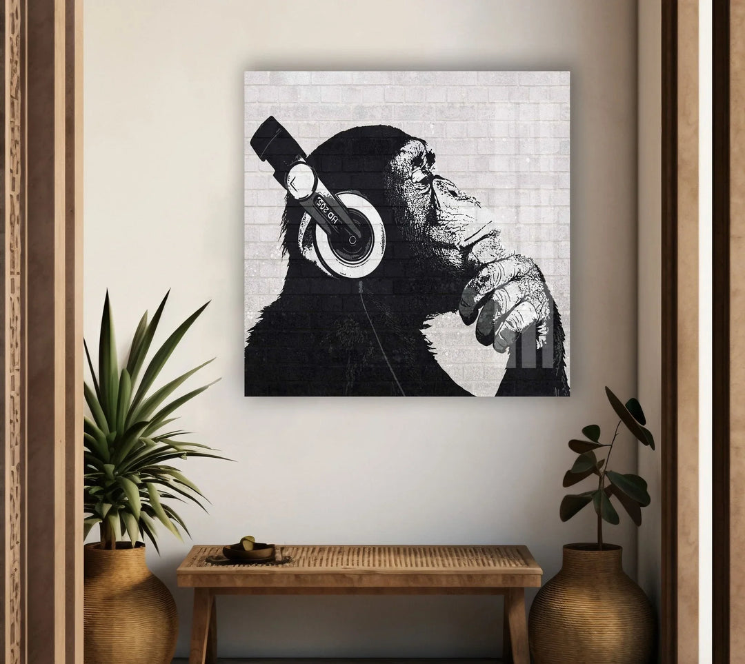Black and white glass wall art featuring a thoughtful chimp wearing large headphones against a brick background.