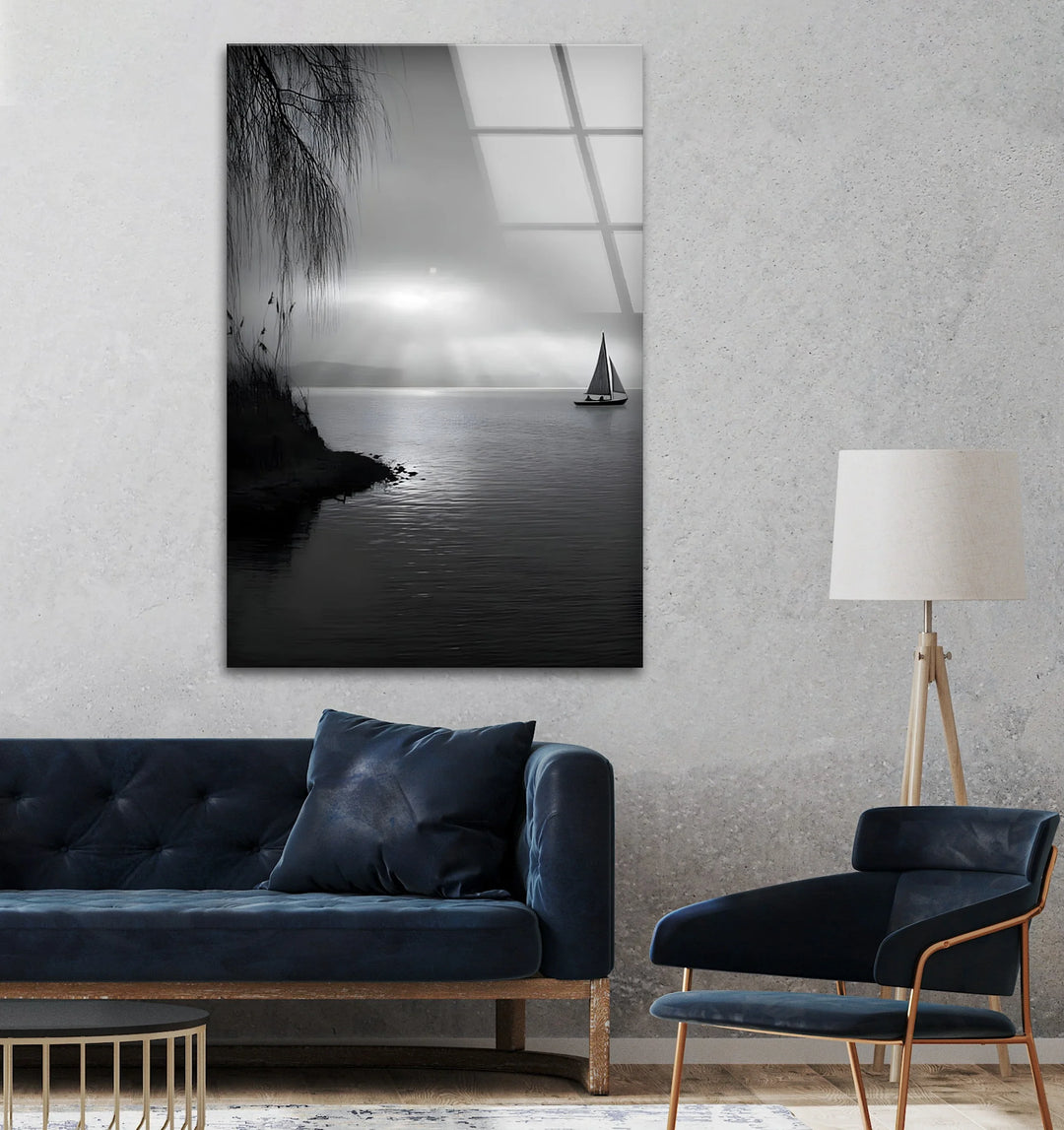 Tranquil black and white scene with a sailboat and shoreline printed on glass wall art.