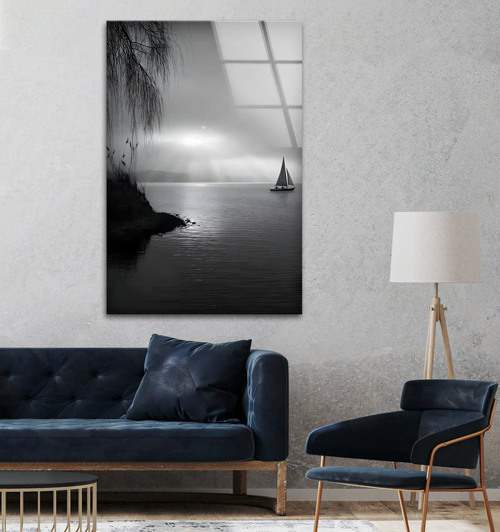 Tranquil black and white scene with a sailboat and shoreline printed on glass wall art.