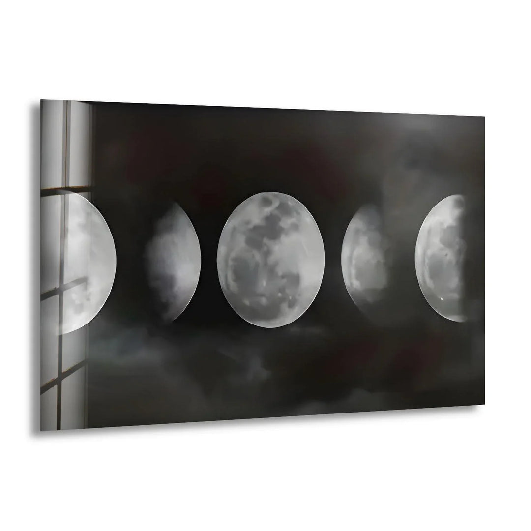 Black and white glass wall art showing multiple moon phases emerging through dark misty clouds.