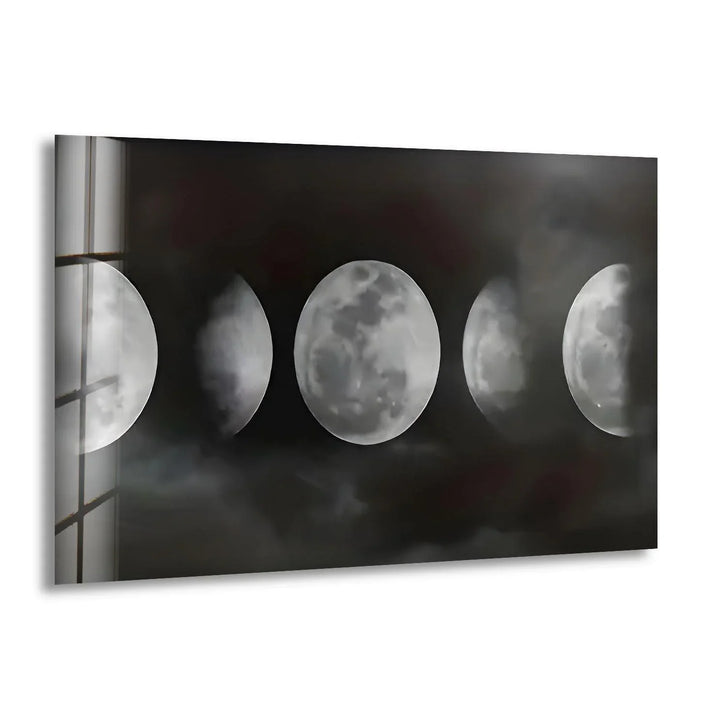 Black and white glass wall art showing multiple moon phases emerging through dark misty clouds.
