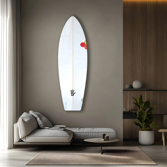 A white surfboard with geometric hexagonal honeycomb patterns in red, yellow, and orange serves as striking glass wall art decor.