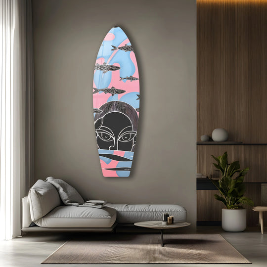 A modern surfboard with a woman's face and fish floats on a smooth, pastel surface, presented as hanging wall art.