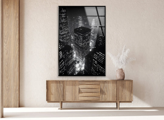 Brightest illuminated skyscrapers dominate this decorative wall art, 'City Lights: A Stunning Black and White Cityscape on Glass Wall Art.'