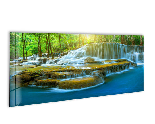Deep Forest Waterfall glass wall art shows a lush forest scene and cascading falls and makes serene wall decor with its vivid colors and natural landscape
