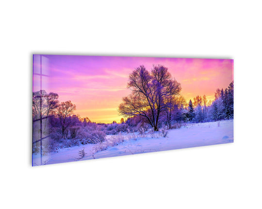 This panoramic glass wall art shows a snowy forest sunset landscape and is winter serenity decor with vibrant colors on tempered glass