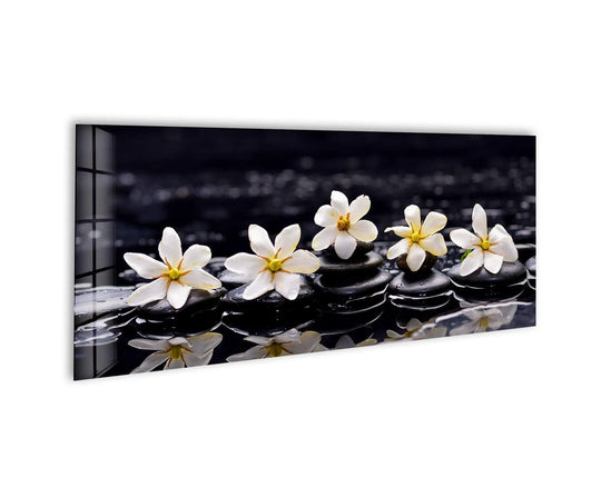 Gardenia With Therapy Stones glass wall art showcases white flowers and black stones and offers spa serenity decor with a glossy finish and horizontal orientation