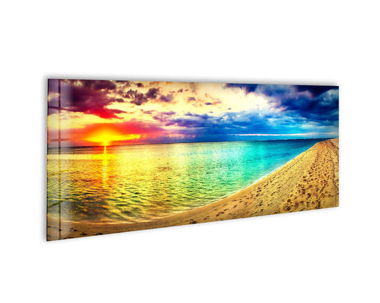 Colorful sunset and beach landscape glass wall art features a vibrant sky and turquoise water and sandy beach with footprints creating modern wall decor