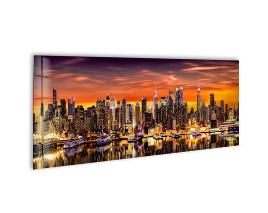 Midtown Manhattan Night glass wall art showcases a vibrant city skyline and reflective water and offers modern wall decor for a large statement wall