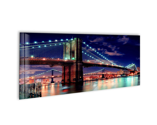 Manhattan Bridge Night landscape glass wall art showcases a vibrant city skyline and illuminated cables and reflects on the water below for modern wall decor