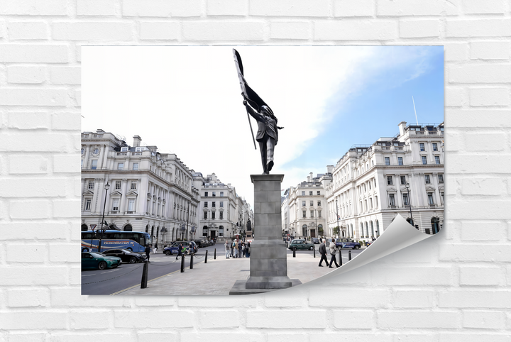 The striking color contrast in this Banksy wall art highlights the dark bronze statue against the brilliant white sky and pale blue patches, perfect for glass printing.