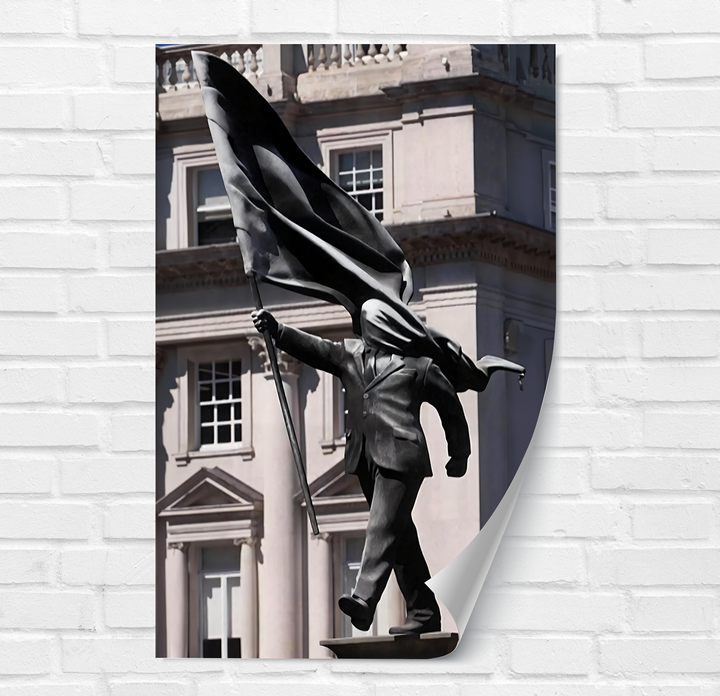 The peeled corner of the Banksy sculpture glass wall art decor shows the dark statue's base and feet against a textured white brick wall.