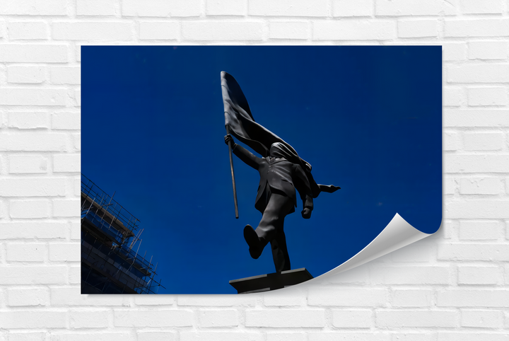 The high color saturation emphasizes the deep sapphire sky behind the dark flag-bearer statue in this best glass art print.
