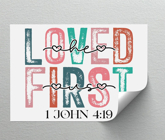 Showing the realistic detail, the 'Loved He First' Christian verse is printed as canvas art with uplifting colors and a distressed texture for a faith-filled home.