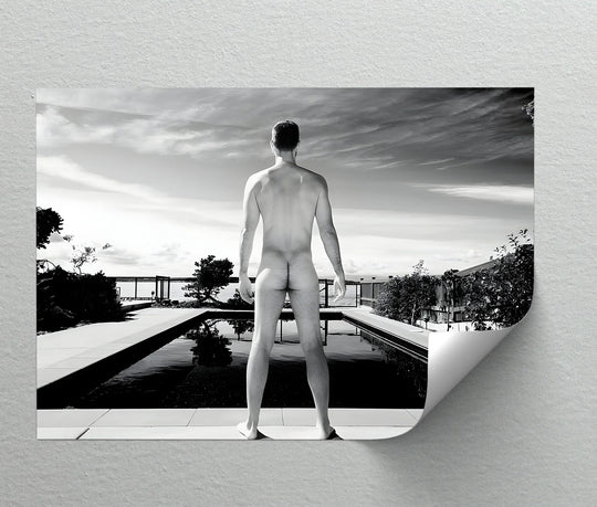 Capturing the surface texture of this framed canvas art print, a striking black and white male nude poised by a reflective pool under a cloudy, bright sky.