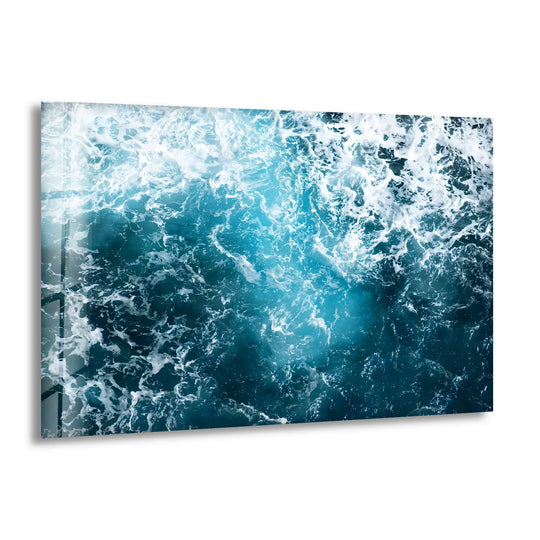 Turbulent depths of deep blue water form an abstract glass wall artwork with swirling white foam.