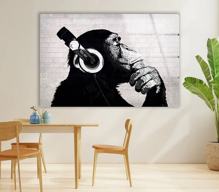 Banksy Black and white modern wall art of a chimpanzee listening to music with a pensive expression.