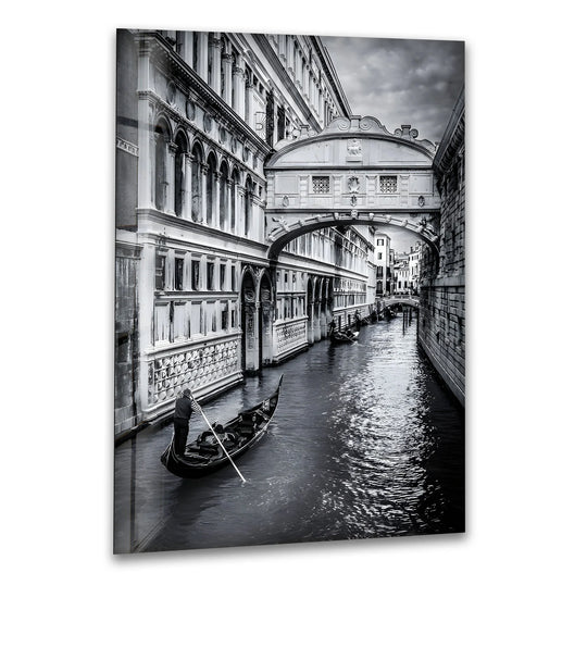 Subtle light and shadow define the arches and canal as a gondola glides beneath the Bridge of Sighs in this piece of art from glass, a black and white Venice wall art.
