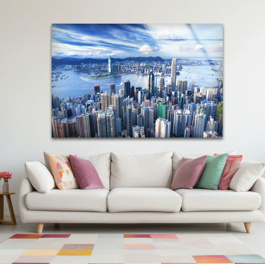 Overlooking the Hong Kong cityscape and harbor, the stunning aerial print wall art presents a sky filled with sweeping blue and white clouds as the background.