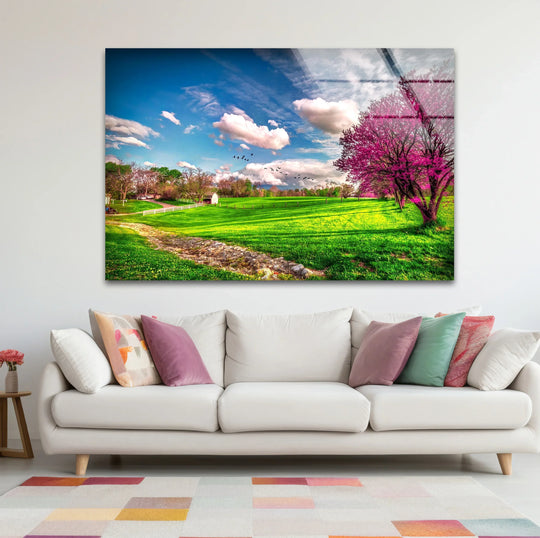 Showcasing vibrant Spring Meadow glass wall art with blooming trees, the central subject exemplifies unique modern wall decor, enhancing the landscape's beauty.