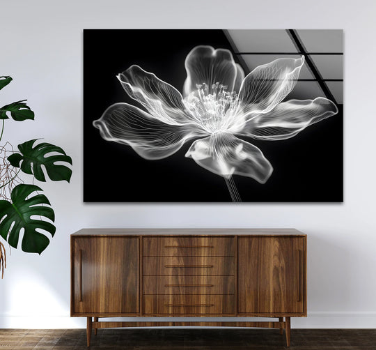 The darkest area highlights a minimalist flower design from the black and white wall art prints, mounted above a wooden cabinet with a potted plant nearby.