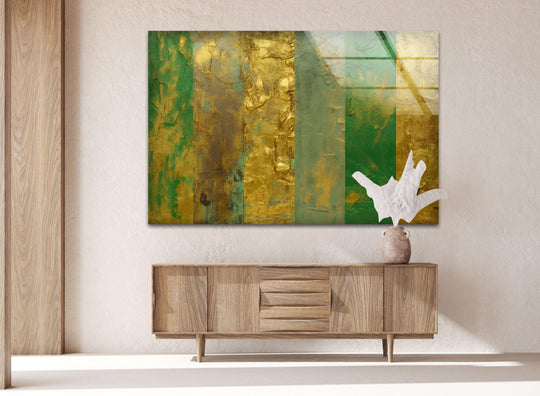 Textured green and gold grunge abstract glass wall artwork displayed above a wooden cabinet.