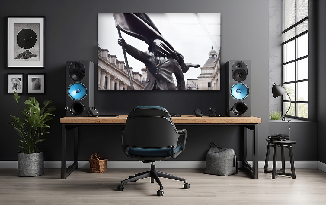 Charcoal tones dominate this modern workspace, highlighting a Banksy Flag Bearer glass print wall art and speakers with a blue glow.