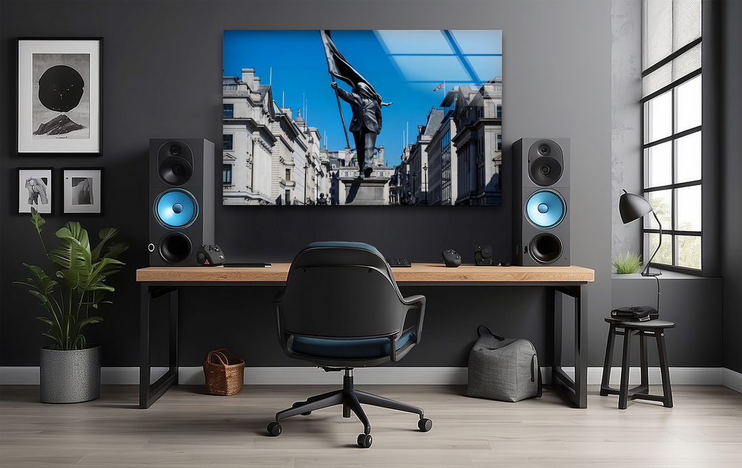 The stillness of a dark-suited statue holding a black flag under a vibrant blue sky is beautifully captured in this striking Banksy glass wall artwork.