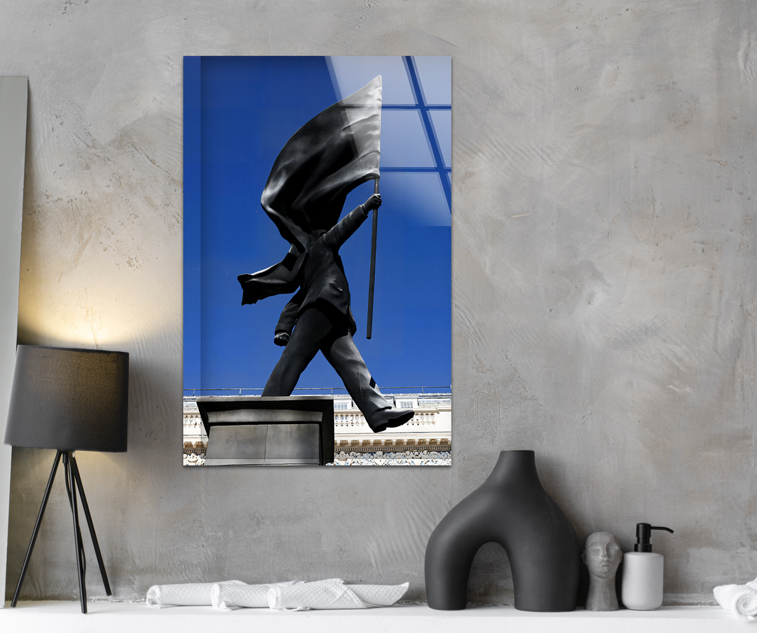 A striking transition from the vivid blue sky behind the grayscale Banksy flag statue to the textured concrete enhances this decorative wall art.