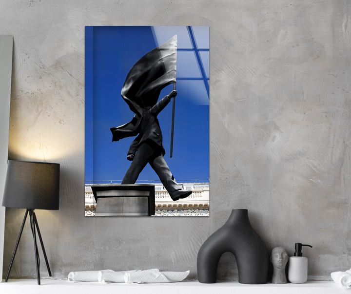 A striking transition from the vivid blue sky behind the grayscale Banksy flag statue to the textured concrete enhances this decorative wall art.
