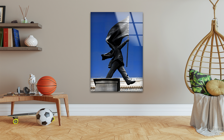 The large Banksy Flag Statue glass printing art piece features clean, defined borders and a glossy finish, reflecting a vivid blue sky.