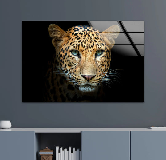 Cool leopard portrait glass printing with piercing turquoise eyes and black rosettes on a dark background.