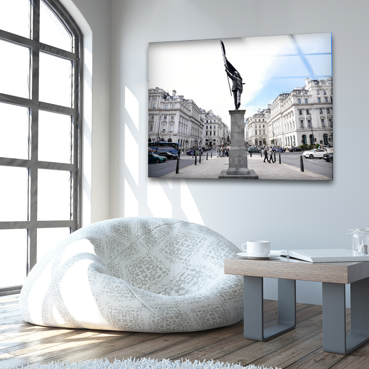 A captivating glass wall prints artwork showcases a dark monument holding a flag, centrally placed in a city square with elegant buildings.