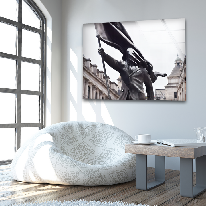 The central subject of this dramatic Banksy Flag Bearer print wall art is a striking monochromatic statue of a figure holding a flowing flag.