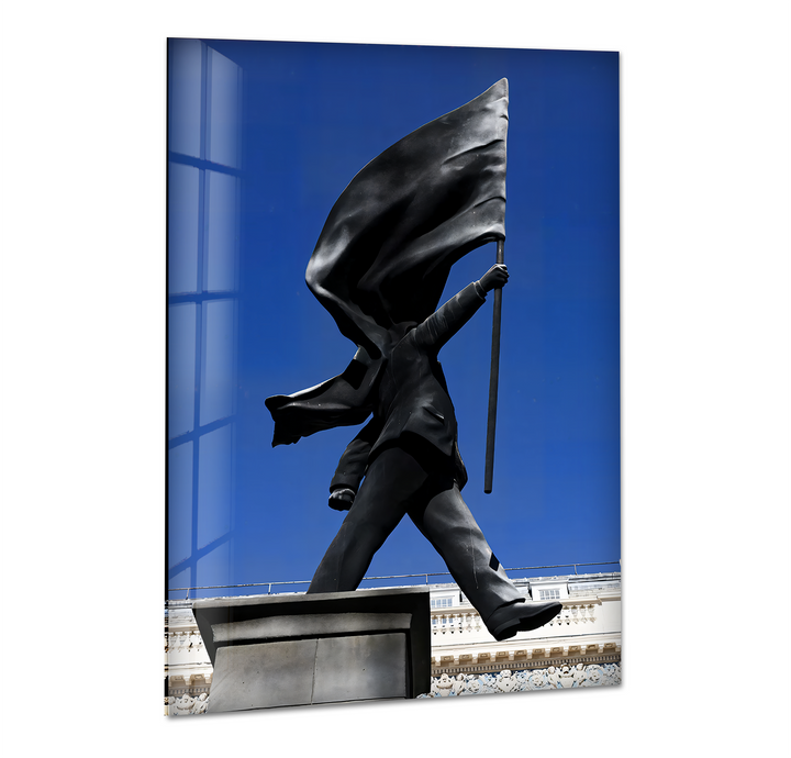 The soft, flowing folds of the black flag held by the iconic Banksy statue stand out against the vibrant blue sky in this glass wall artwork.