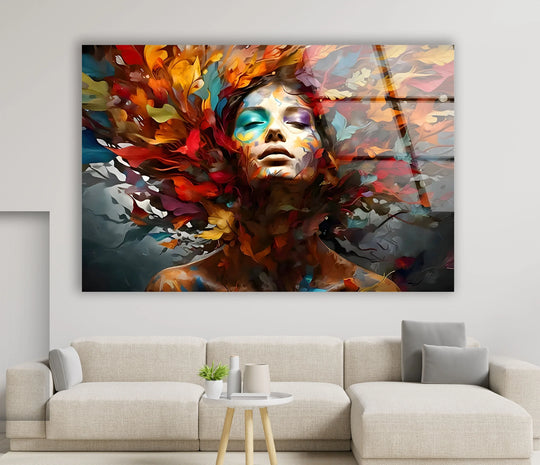 Abstract glass art depicts a woman's face emerging from a vibrant, swirling explosion of colorful autumnal leaves.