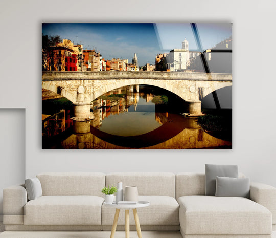 Vibrant color saturation enhances this Girona Bridge glass wall art, capturing the scenic view and its reflected image for captivating home decor.