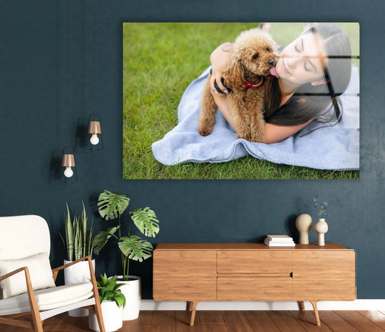 Dark teal walls complement a cozy room with a plush chair and a glass wall art piece featuring a poodle licking a woman's cheek.