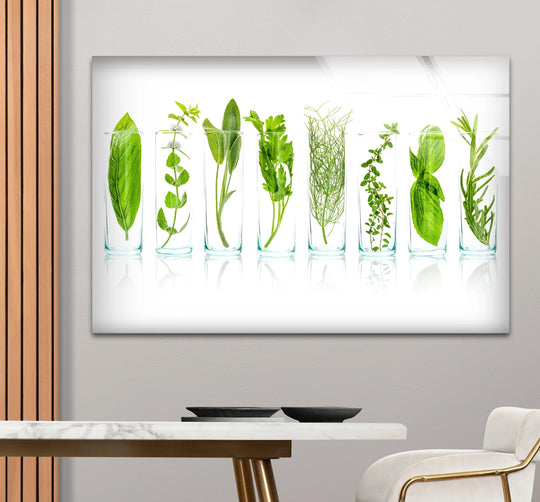 Horizontal glass wall art featuring a botanical print of fresh green culinary herbs in glass jars displayed above a white marble table for modern kitchen decor.