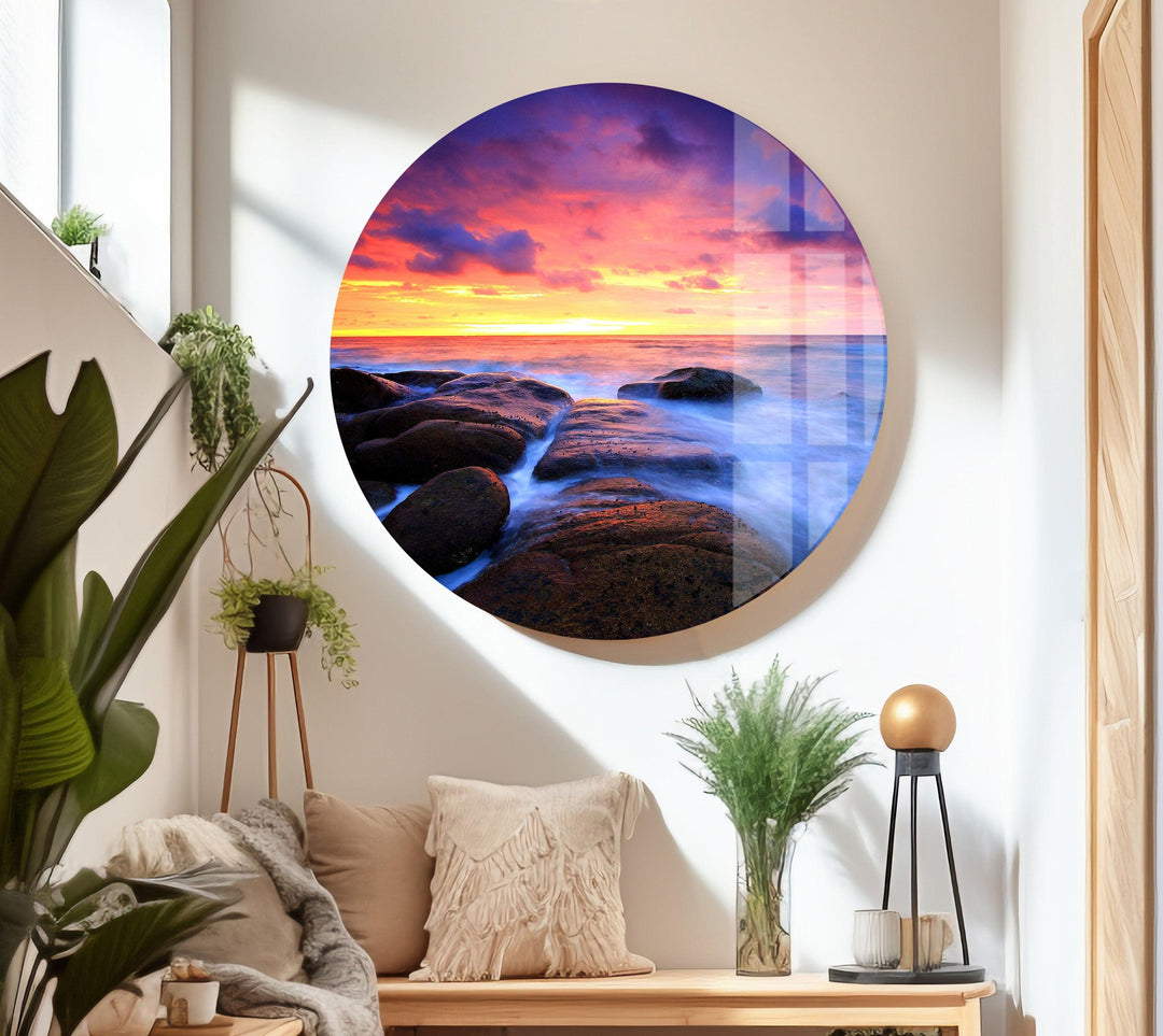 Nature-inspired glass wall art featuring a peaceful sunset over the sea and coastal rocks.
