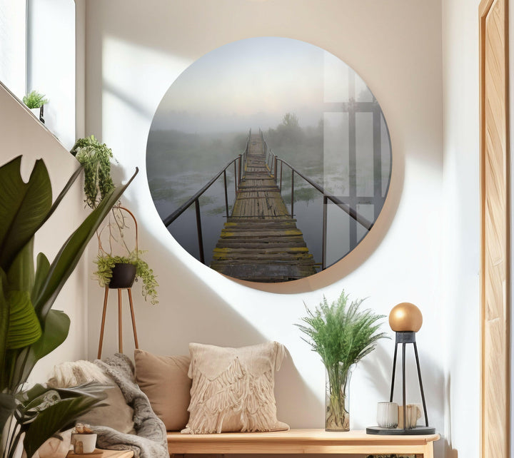 A wooden bridge with metal railings stretching across a mist-covered lake.
