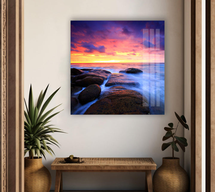 Serene ocean scene with a golden sunset reflecting over rocky shores, printed on glass.
