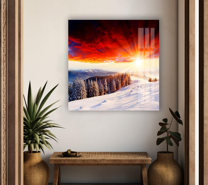 Stunning winter scenery with snow-capped trees and a fiery sky.
