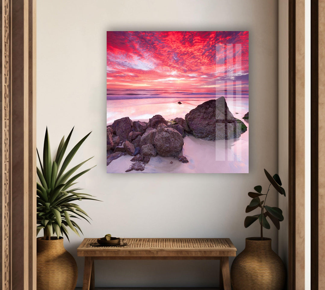Glass wall art showcasing a mesmerizing pink and orange beach sunset.
