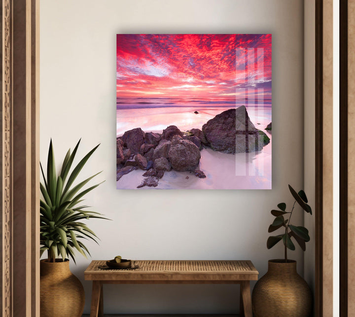 Glass wall art showcasing a mesmerizing pink and orange beach sunset.
