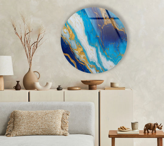 Foreground features a fringed pillow on a couch, complementing the ocean veins round blue marble glass wall art and enhancing the home decor.