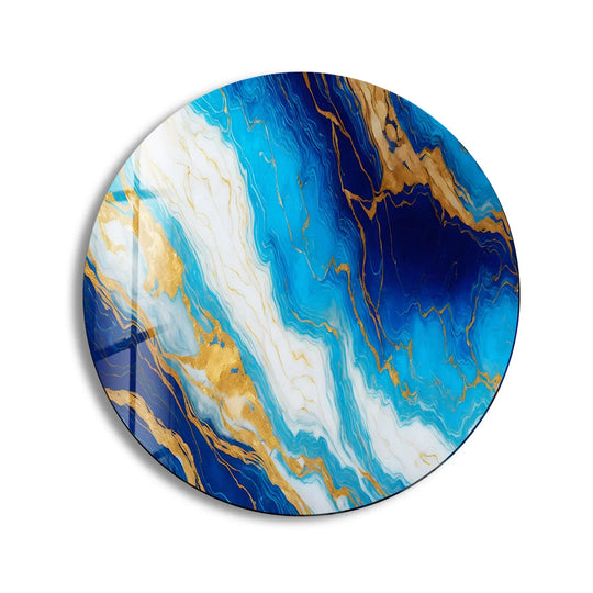 Softly swirling white patterns flow through the round ocean veins glass decorative wall art, contrasting against the deeper blues and shimmering gold accents.