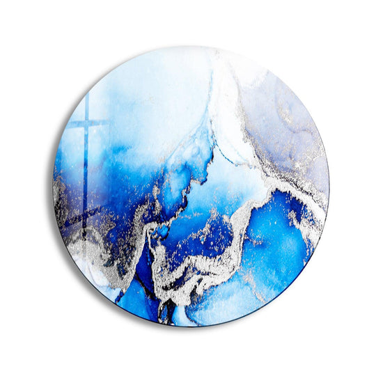 Swirling blues and shimmering silvers converge, suggesting a dynamic dance in this blue marble round glass wall art decor piece.